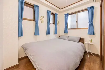 a bedroom with blue curtains and a large bed at \u53f0\u6771\u533a\u5e83\u3005\u5439\u304d\u629c\u3051\u30ea\u30d3\u30f3\u30b0\u306e\u30e1\u30be\u30cd\u30c3\u30c8\u30bf\u30a4\u30d7\u306e\u304a\u5bb6 in Tokyo