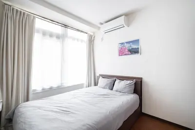 a bed in a room with a large window at 3\u30d9\u30c3\u30c9\u30eb\u30fc\u30e0\u3068\u30ea\u30d3\u30f3\u30b0 4\u90e8\u5c4b\u5168\u3066\u500b\u5ba4 \u6df7\u307e\u306a\u30442\u3064\u306e\u30b7\u30e3\u30ef\u30fc\u30eb\u30fc\u30e0\u3068\u30c8\u30a4\u30ec \u6771\u65b0\u5bbf\u99c52\u52068\u540d in Tokyo