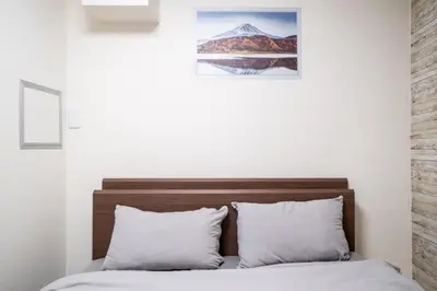 a bed with white pillows and a picture on the wall at 3\u30d9\u30c3\u30c9\u30eb\u30fc\u30e0\u3068\u30ea\u30d3\u30f3\u30b0 4\u90e8\u5c4b\u5168\u3066\u500b\u5ba4 \u6df7\u307e\u306a\u30442\u3064\u306e\u30b7\u30e3\u30ef\u30fc\u30eb\u30fc\u30e0\u3068\u30c8\u30a4\u30ec \u6771\u65b0\u5bbf\u99c52\u52068\u540d in Tokyo