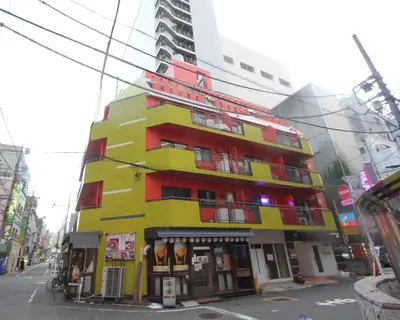 a yellow and red building on a city street at LUANAHOTEL IN KABUKICHO in Tokyo