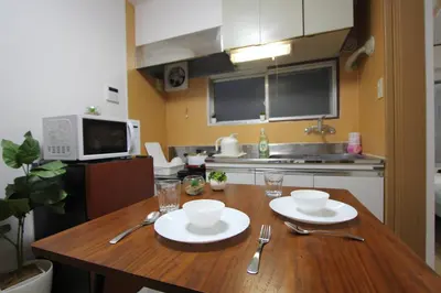 a kitchen with a wooden table with plates and silverware at LUANAHOTEL IN KABUKICHO in Tokyo