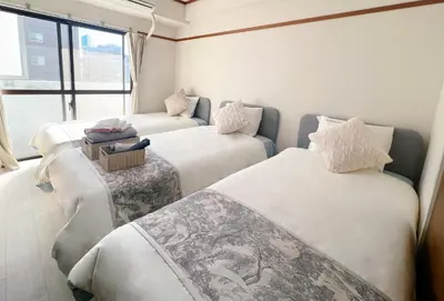 a room with three beds and a window at Emoto Asakusa in Tokyo