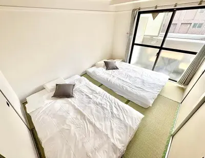 two beds in a small room with a window at Emoto Asakusa in Tokyo