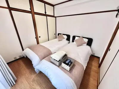 two beds in a room with white walls and wood floors at Emoto Asakusa in Tokyo