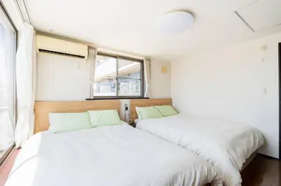two beds in a room with a window at FUJIMI TOWN HOUSE in Tokyo