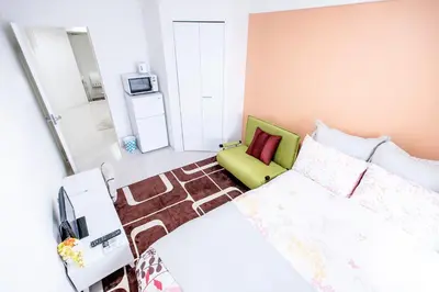 a small bedroom with a bed and a green chair at Shinjuku Ryokan Retreat丶Local Tokyo Experience & Short Trips Hub丶walk to Higahsi Shinjuku station LoE2 in Tokyo