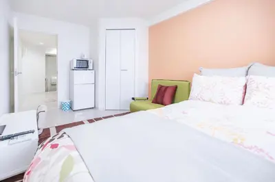 a bedroom with a white bed and a green chair at Shinjuku Ryokan Retreat丶Local Tokyo Experience & Short Trips Hub丶walk to Higahsi Shinjuku station LoE2 in Tokyo