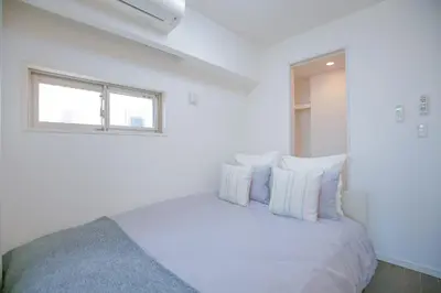 a white bedroom with a bed with pillows and a window at 10min walk to Shinjuku YEoE-2 in Tokyo