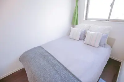 a bedroom with a white bed with pillows and a window at 10min walk to Shinjuku YEoE-2 in Tokyo