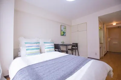 a bedroom with a large white bed and a table at walk to Higahsi Shinjuku sta. SYW in Tokyo