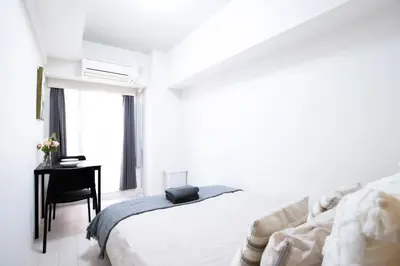 a white bedroom with a bed and a desk at walk to Higahsi Shinjuku sta. LoL in Tokyo