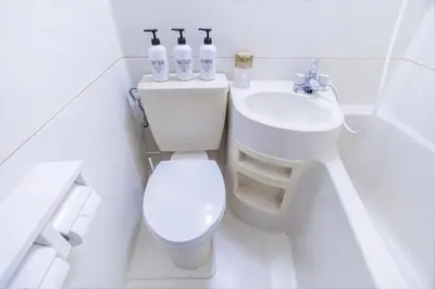 a white bathroom with a toilet and a sink at walk to Higahsi Shinjuku sta. LoL in Tokyo