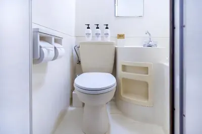 a white bathroom with a toilet and a sink at walk to Higahsi Shinjuku sta. LoL in Tokyo