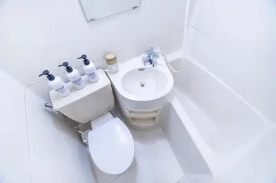 a white bathroom with a toilet and a sink at walk to Higahsi Shinjuku sta. LoL in Tokyo
