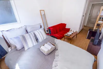 a bedroom with a large bed with a red couch at walk to Higahsi Shinjuku sta. EoQ in Tokyo