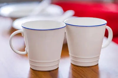 two white coffee mugs sitting on a table at walk to Higahsi Shinjuku sta. EoQ in Tokyo