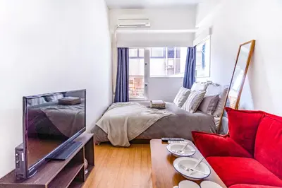 a living room with a bed and a red couch at walk to Higahsi Shinjuku sta. EoQ in Tokyo