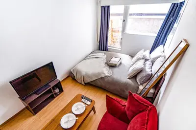 a small bedroom with a bed and a television at walk to Higahsi Shinjuku sta. EoQ in Tokyo