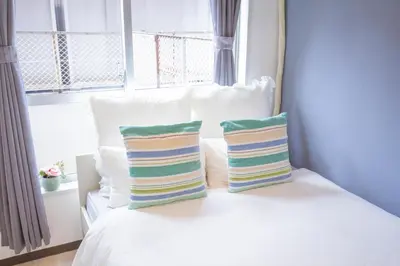 a bed with two pillows on it with a window at walk to Higahsi Shinjuku sta. EYW in Tokyo