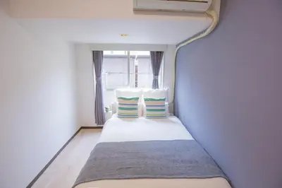 a small bed in a room with a window at walk to Higahsi Shinjuku sta. EYW in Tokyo