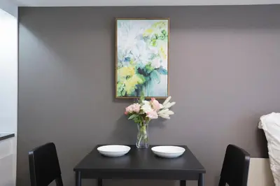a table with a vase of flowers and a painting at walk to Higahsi Shinjuku sta. LYo in Tokyo