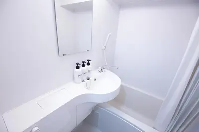 a white bathroom with a sink and a mirror at walk to Higahsi Shinjuku sta. LYo in Tokyo