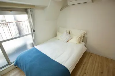 a small bed in a room with a window at walk to Higahsi Shinjuku sta. WoSI in Tokyo