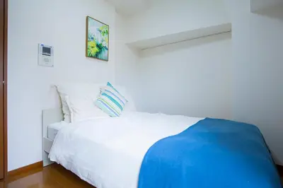 a bedroom with a white bed with a blue blanket at walk to Higahsi Shinjuku sta. SIoQ-2 in Tokyo