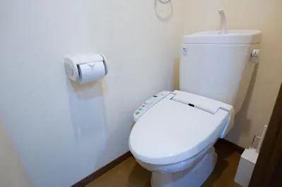 a white toilet in a bathroom with a toilet paper dispenser at walk to Higahsi Shinjuku sta. SIoQ-2 in Tokyo