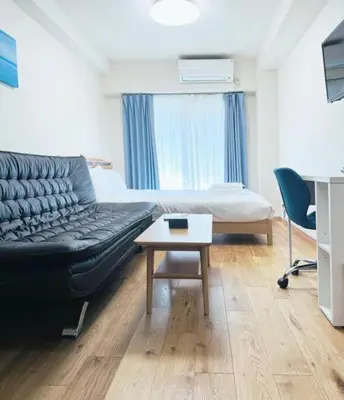 a living room with a couch and a bed and a table at We Guest House in Tokyo
