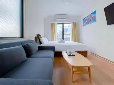 a room with a couch and a bed and a table at We Guest House in Tokyo