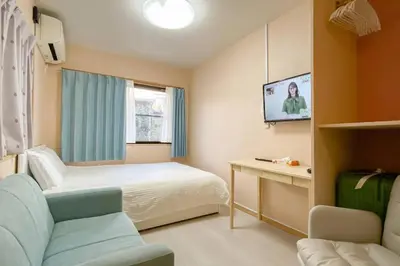 a hotel room with a bed and a tv at We Guest House in Tokyo