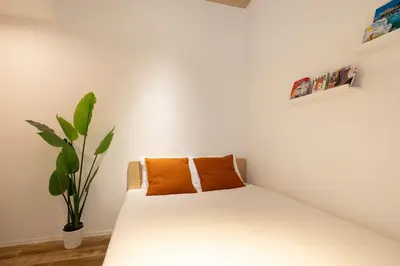 a bedroom with a white bed with an orange pillow at Kisetsu\u5927\u68eeII in Tokyo