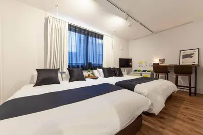 two beds in a room with a table and a desk at Trym\u62bc\u4e0a in Tokyo
