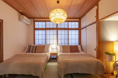 a room with three beds and a chandelier at \u5317\u65b0\u5bbf1-11-10 in Tokyo
