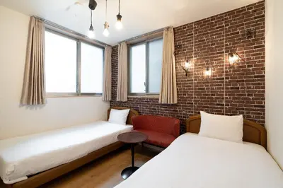 a room with two beds and a red chair at City Oasis in Tokyo