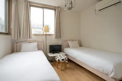 two beds in a small room with a window at City Oasis in Tokyo