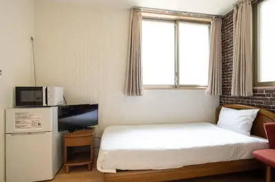 a small hotel room with a bed and a television at City Oasis in Tokyo