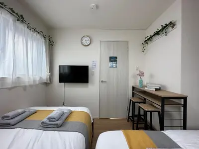a bedroom with two beds and a desk and a tv at nestay villa tokyo oyama in Tokyo