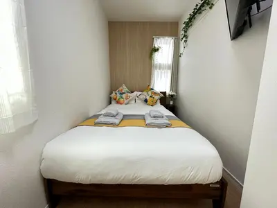 a small bedroom with a bed with white sheets at nestay villa tokyo oyama in Tokyo