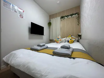a bedroom with a large bed with towels on it at nestay villa tokyo oyama in Tokyo