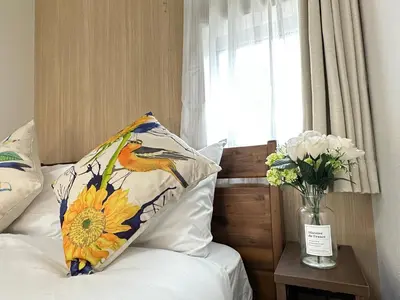 a bed with a pillow and a vase of flowers at nestay villa tokyo oyama in Tokyo