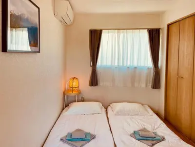 a small bedroom with two beds and a window at \u4e1c\u4eac\u65b0\u5bbf\u533a\u65e9\u7a3b\u7530\u5730\u94c1\u6b65\u884c5\u5206\u949fViewing House in Tokyo