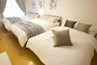 three beds in a room with white sheets and pillows at Generous Forest 201 in Tokyo