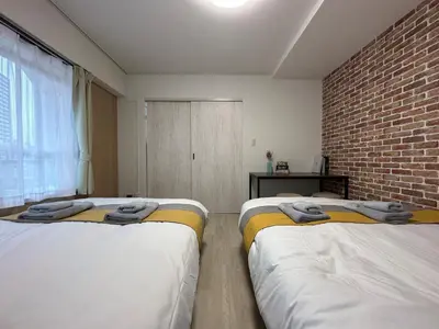 two beds in a room with a brick wall at nestay apartment tokyo otsuka in Tokyo
