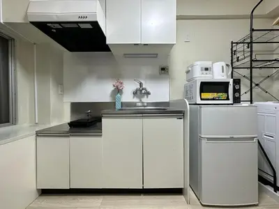 a kitchen with white cabinets and a microwave at nestay apartment tokyo otsuka in Tokyo