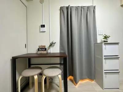 a table with two chairs next to a curtain at nestay apartment tokyo otsuka in Tokyo