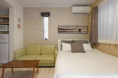 a bedroom with a bed and a couch and a table at Livion III in Tokyo