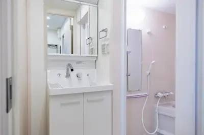 a white bathroom with a sink and a shower at Livion III in Tokyo