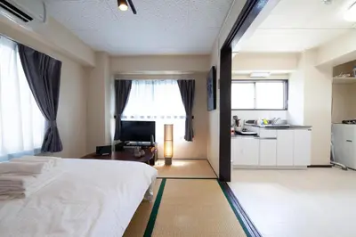 a bedroom with a white bed and a kitchen at YK building in Tokyo